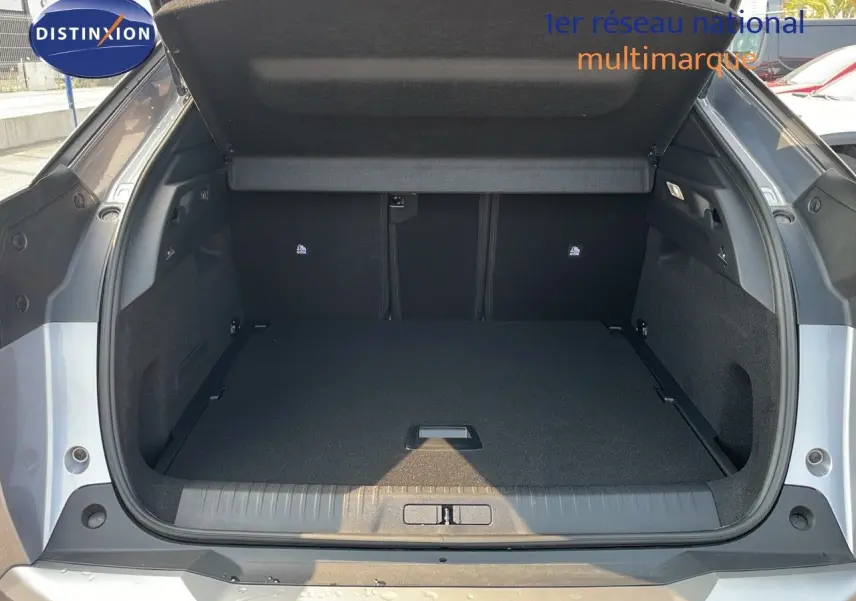 Coffre ouvert vu de l'arrière d'un Peugeot 3008 Hybrid gris Artense métal, montrant un espace de chargement vide.