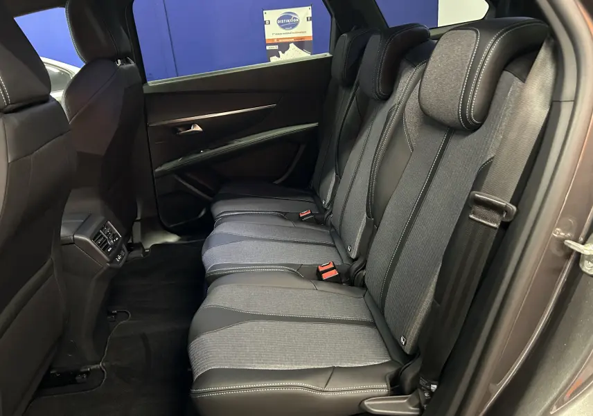 Vue latérale droite de l'habitacle arrière du Peugeot 5008 2024 gris Platinium, sièges tissu et cuir avec surpiqûres blanches.