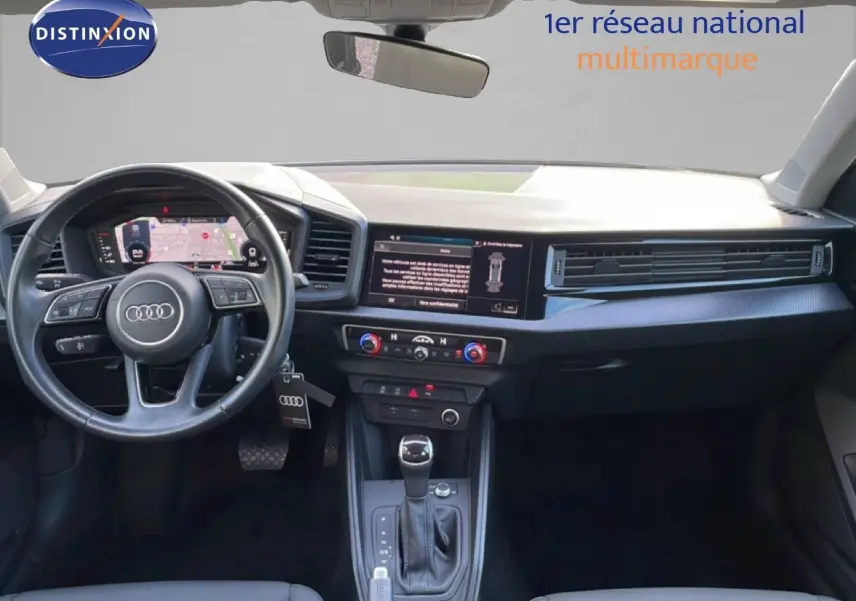 Vue intérieure avant de l'Audi A1 Sportback 2023, tableau de bord moderne avec écran digital et volant multifonction noir.