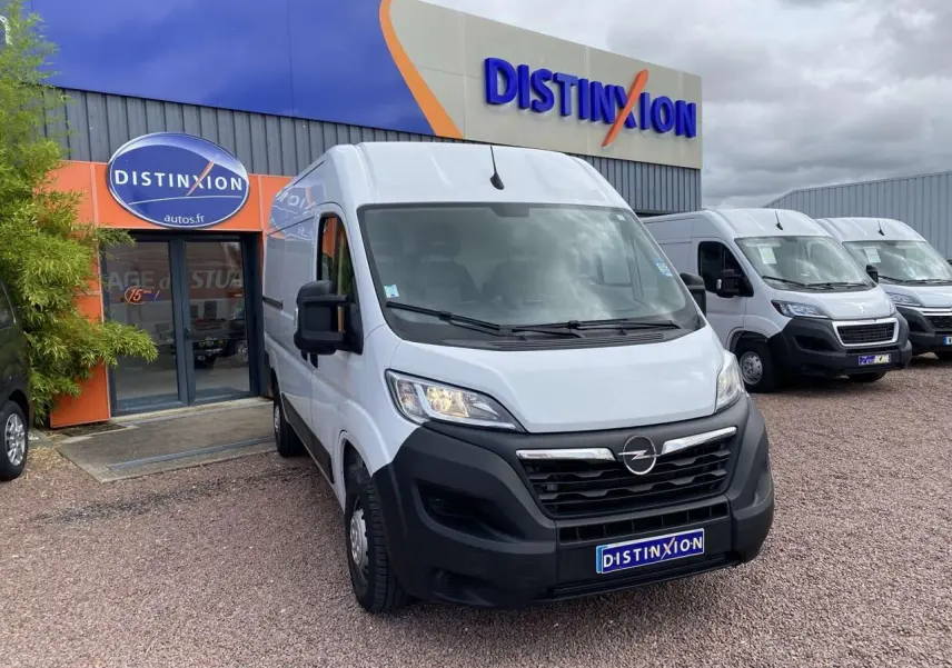 Vue 3/4 avant d’un Opel Movano blanc stationné devant un bâtiment avec logo Distinxion.