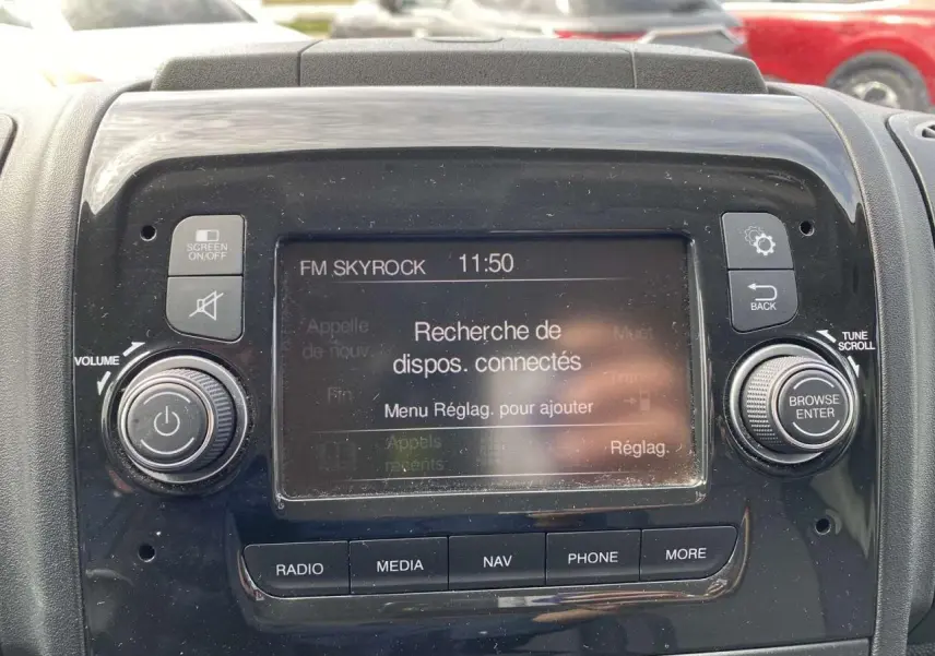 Vue rapprochée de l’écran multimédia noir du tableau de bord de l’Opel Movano Fourgon blanc, affichant la recherche de dispositifs connectés.