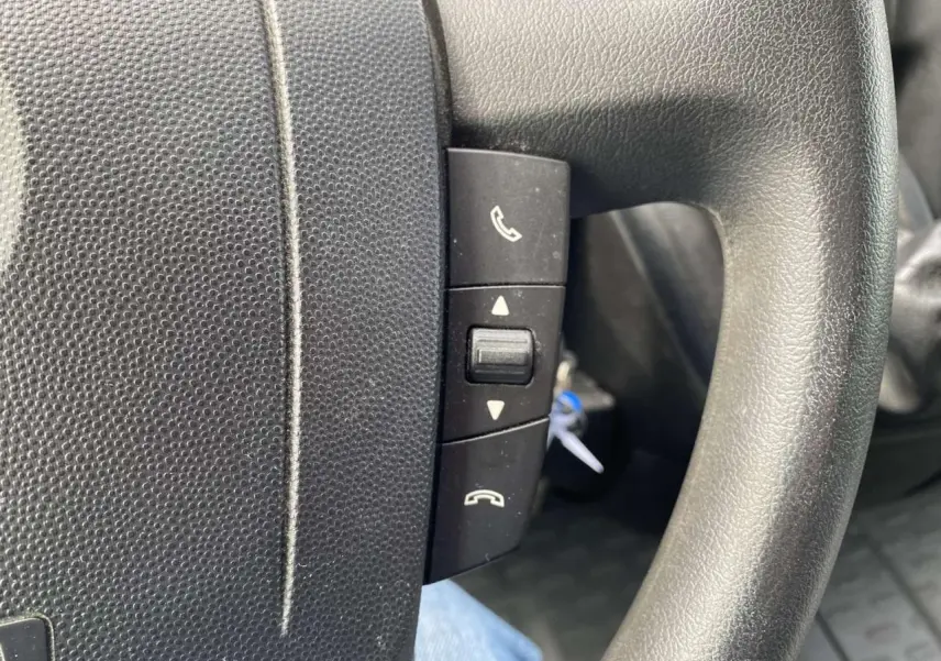 Gros plan sur les commandes téléphoniques au volant noir de l’Opel Movano Fourgon blanc de 2022.