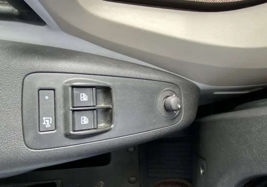 Gros plan sur les commandes de lève-vitres et réglage des rétroviseurs côté conducteur de l’Opel Movano Fourgon blanc.