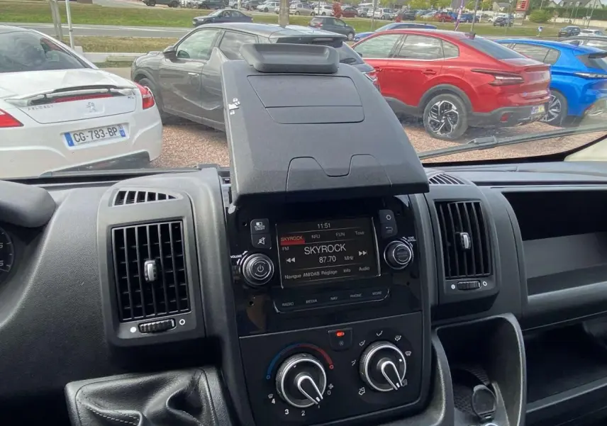 Vue intérieure centrée sur la console centrale de l'Opel Movano blanc, avec écran radio et commandes de climatisation visibles.