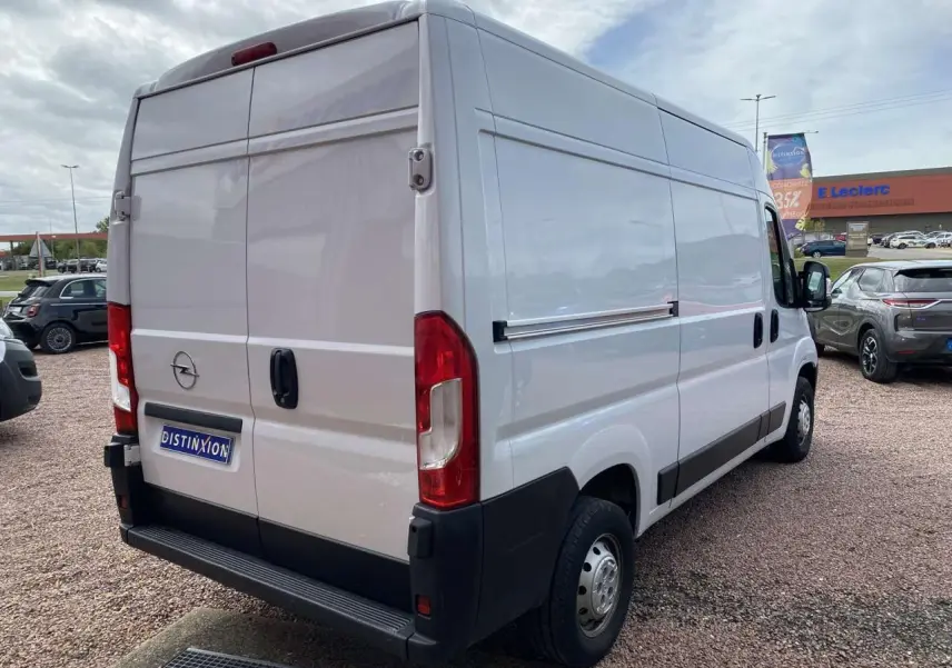 Vue 3/4 arrière droite d’un Opel Movano Fourgon blanc avec portes arrière battantes tôlées sur un parking.
