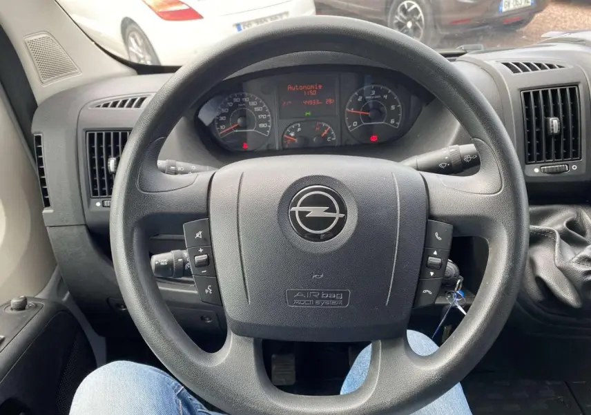 Vue intérieure centrée sur le volant noir d'un Opel Movano Fourgon 2022 avec levier de vitesses manuel à droite.