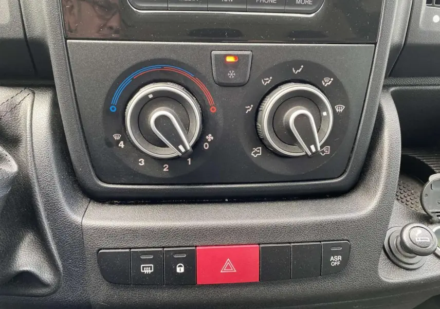 Gros plan sur la console centrale de l’Opel Movano Fourgon 2022, avec commandes de climatisation manuelle et boutons de sécurité.