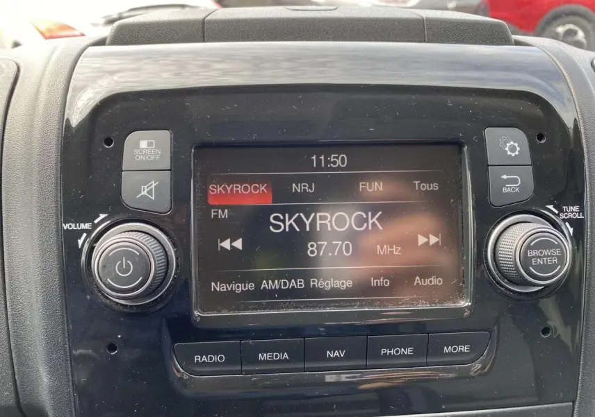 Gros plan sur l’écran multimédia noir du tableau de bord de l’Opel Movano Fourgon affichant la radio Skyrock.