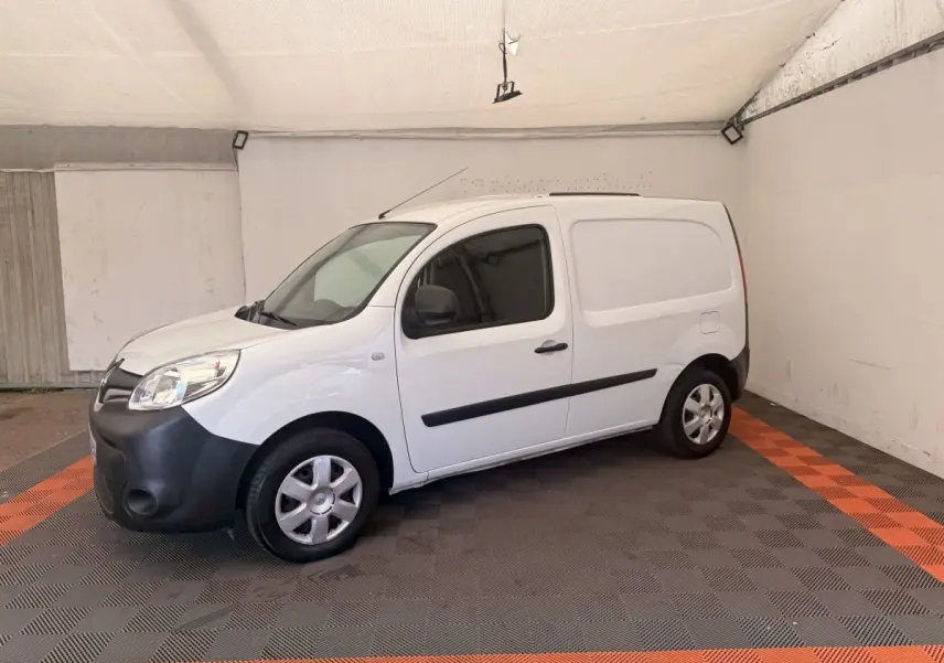 Renault Kangoo blanc en 3/4 avant droit, fourgonnette avec pare-chocs noir et vitres teintées.