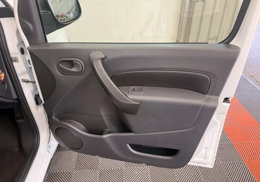 Vue intérieure de la porte avant gauche du Renault Kangoo blanc, avec poignée et commande de vitre électrique.