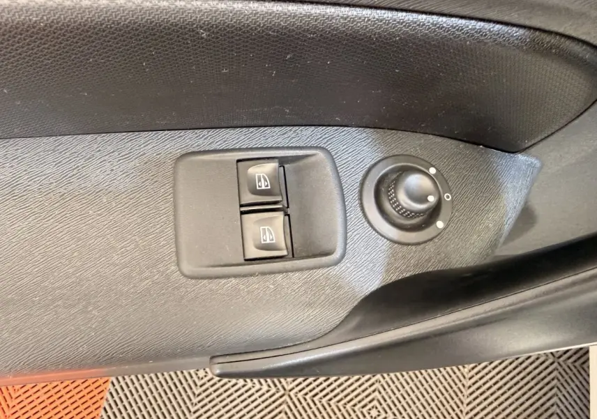 Détail des commandes de lève-vitres et réglage des rétroviseurs sur la porte côté conducteur d’un Renault Kangoo blanc.