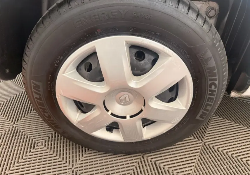 Gros plan sur la roue avant droite d'un Renault Kangoo blanc avec jante acier et logo Renault au centre.