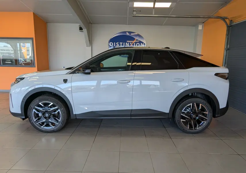 Vue latérale gauche d’un Peugeot 3008 blanc Okenite avec toit noir et jantes alliage bicolores en intérieur showroom.
