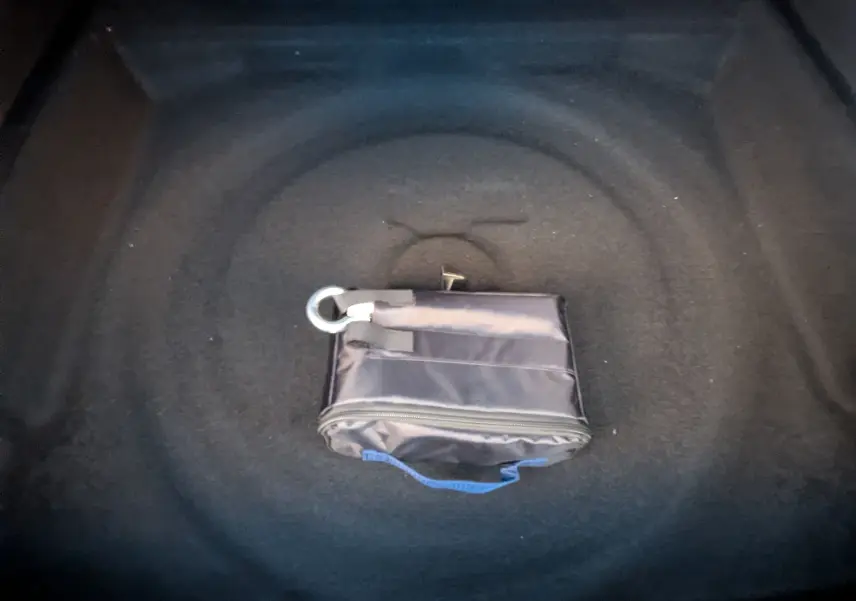 Vue intérieure du coffre d’un Peugeot 3008 blanc Okenite 2026, avec une trousse de réparation pneumatique noire posée au centre.