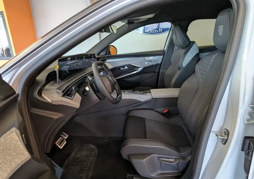 Vue intérieure côté conducteur du Peugeot 3008 blanc Okenite 2026, avec sièges sport et tableau de bord moderne.
