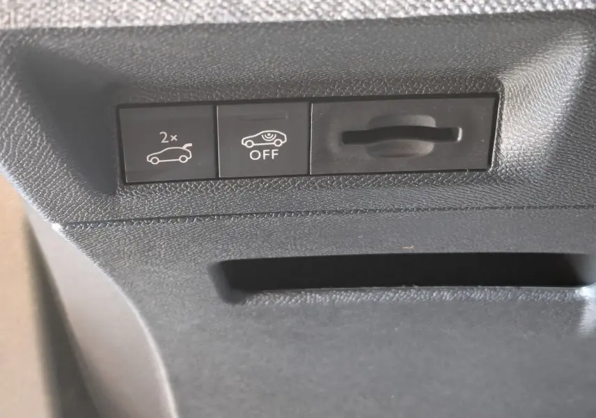 Gros plan sur les commandes intérieures noires du coffre et de l'assistance au stationnement du Peugeot 3008 blanc Okenite.