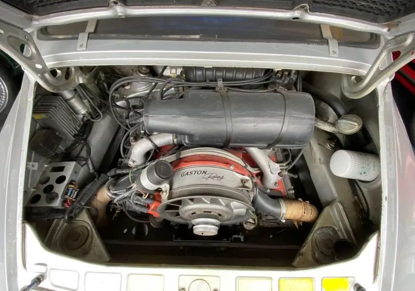 Vue plongeante sur le moteur arrière d’une Porsche 911 3.0 SC gris métallisé avec marquage Gaston Racing visible.