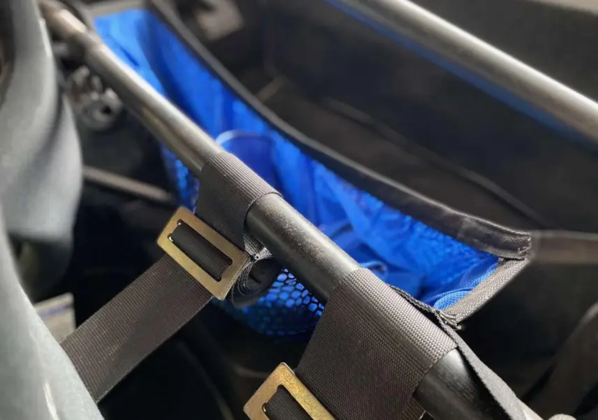 Détail intérieur montrant l’arceau cage tubulaire noir et le filet porte-paquets bleu sur Porsche 911 3.0 SC 1980 gris métallisé.