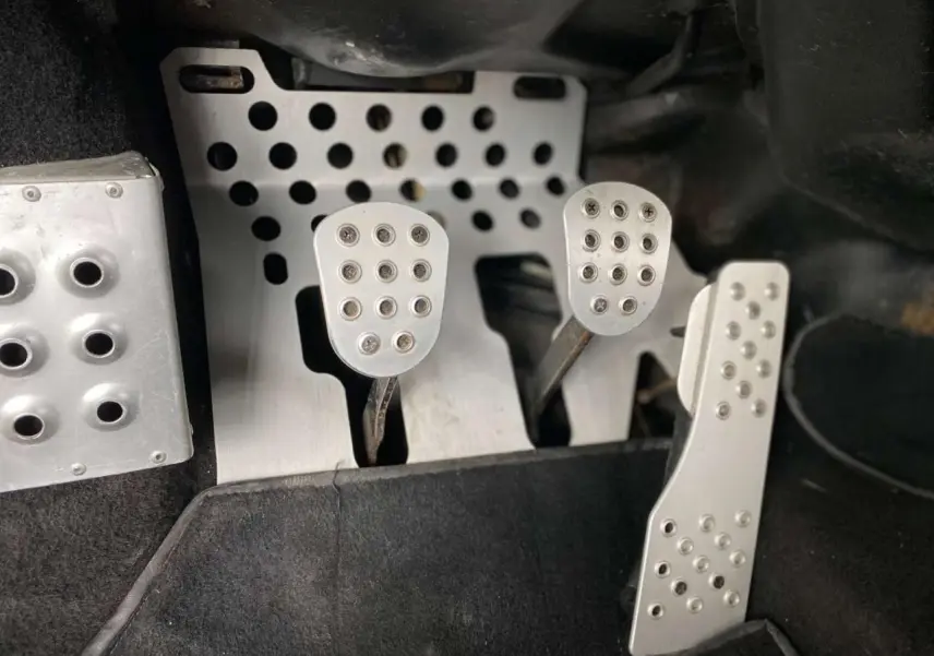 Gros plan sur les pédales en aluminium perforé de la Porsche 911 3.0 SC 930 Kg homologuée route, intérieur noir.