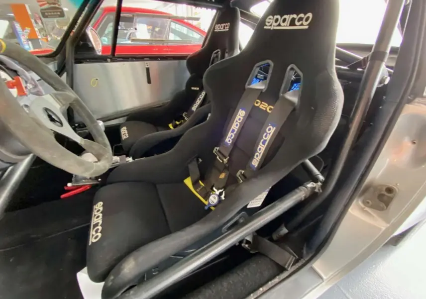 Intérieur de Porsche 911 3.0 SC gris, vue côté conducteur, sièges baquets Sparco avec harnais et arceau tubulaire.