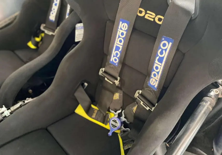 Gros plan sur les baquets Sparco noirs avec harnais 6 points dans l’habitacle d’une Porsche 911 3.0 SC gris métallisé.