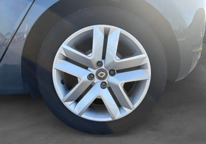 Gros plan sur la roue avant droite d'une Renault Clio gris foncé, mettant en valeur la jante alliage au design moderne.