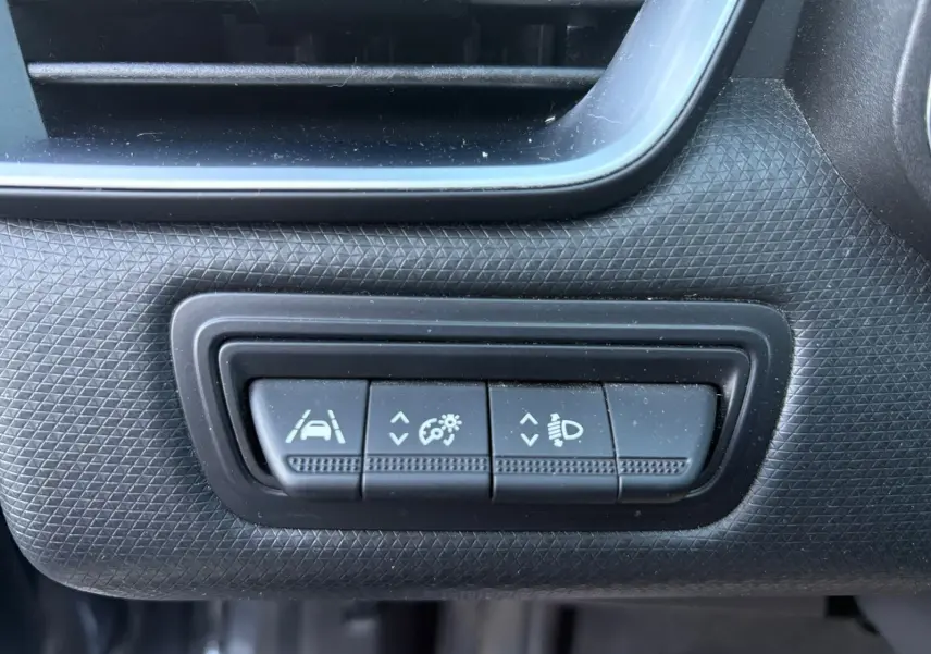 Gros plan sur les commandes d'aide à la conduite et réglage des phares dans l'habitacle d'une Renault Clio gris foncé 2021.