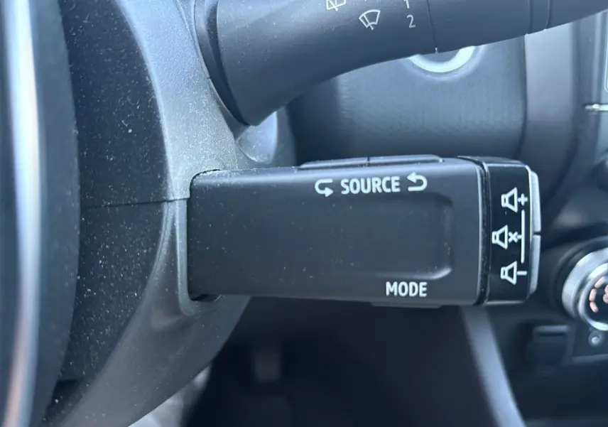 Gros plan sur la commande au volant droite de la Renault Clio gris foncé 2021, avec boutons source et mode visibles.
