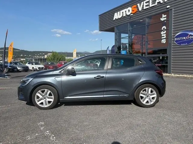 Vue de profil côté gauche d'une Renault Clio gris foncé 2021 garée devant un concessionnaire Autos Velay.