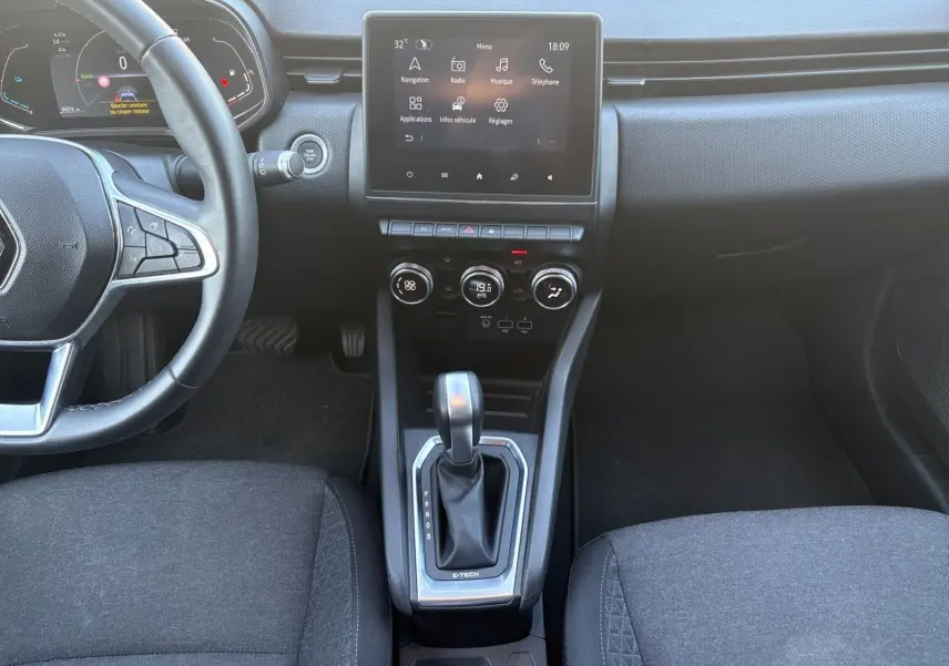 Vue intérieure centrée sur la console centrale et levier de vitesse de la Renault Clio 1.6 E-TECH Business gris foncé avec écran tactile.