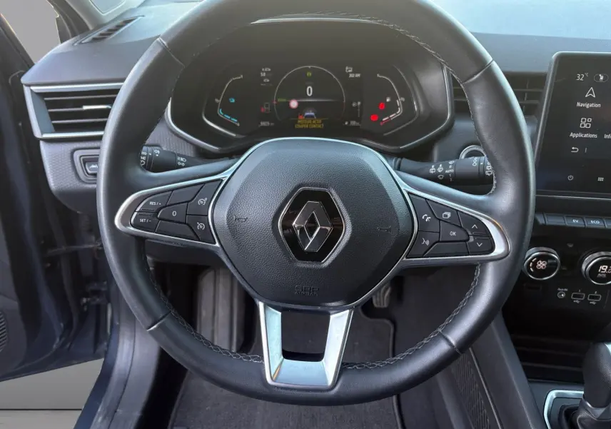 Vue rapprochée du volant noir de la Renault Clio gris foncé 2021, avec tableau de bord digital et commandes intégrées.