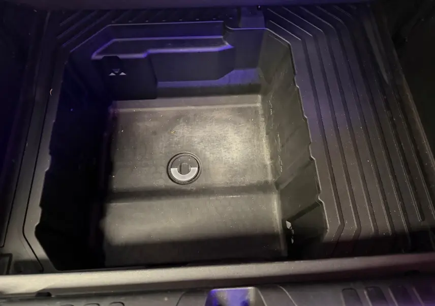 Vue plongeante sur le coffre de rangement sous plancher du Ford Puma gris 2021, espace vide et compartimenté.