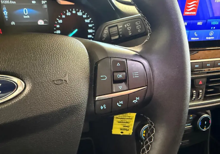 Vue intérieure centrée sur le volant noir de la Ford Puma 2021, avec commandes multifonctions et tableau de bord digital.