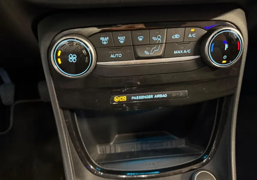 Vue rapprochée de la console centrale du Ford Puma gris 2021, montrant les commandes de climatisation et l'indicateur d'airbag passager.
