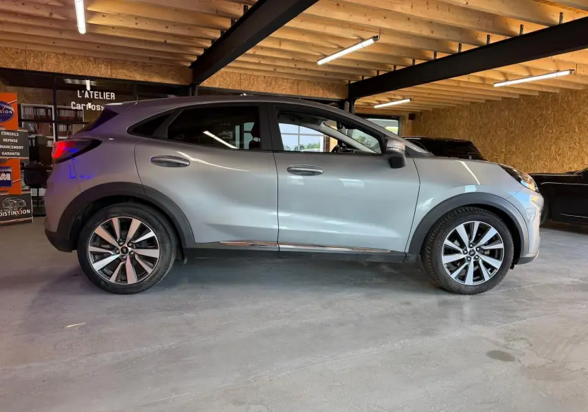 Vue latérale gauche d'un Ford Puma gris 2021 en intérieur, soulignant ses jantes alliage et lignes modernes.