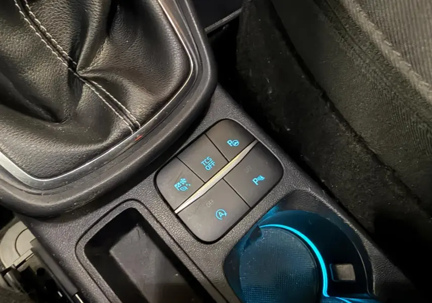 Gros plan sur la console centrale du Ford Puma gris 2021, montrant le levier de vitesse manuel et les boutons de contrôle éclairés.