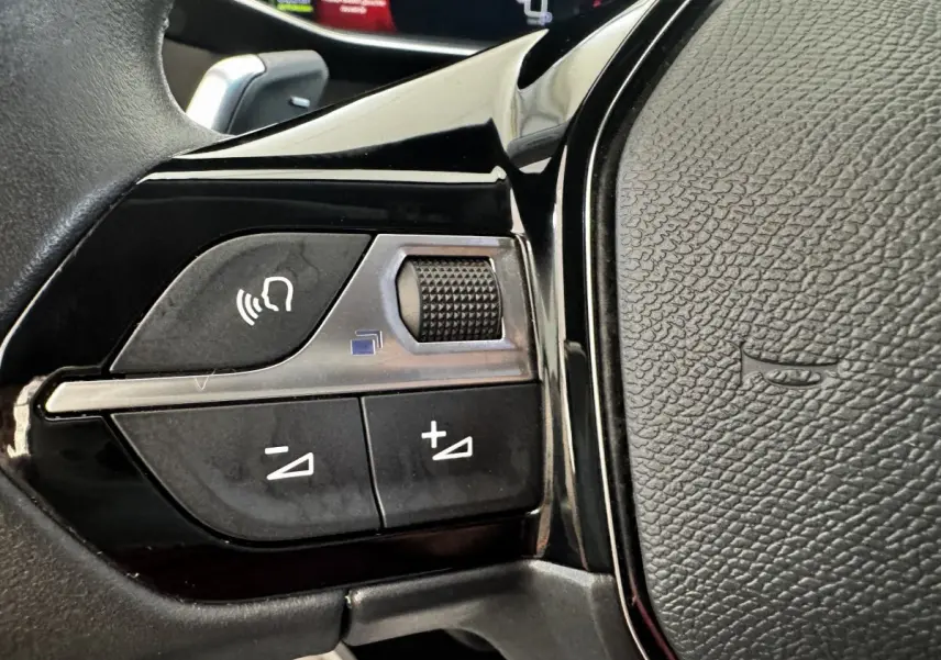 Gros plan sur les commandes vocales et volume du volant cuir noir du Peugeot 2008 BlueHDi 130 Allure Pack 2022.