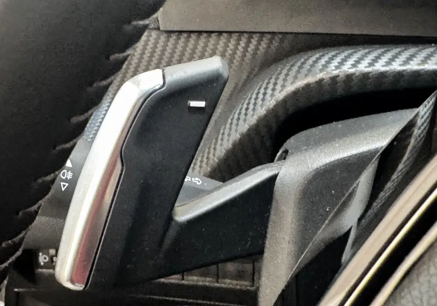 Gros plan sur la palette de changement de vitesse en carbone et métal à gauche du volant du Peugeot 2008 noir.