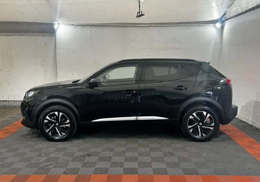 Peugeot 2008 noir vue de profil côté gauche dans un garage, avec jantes alliage bicolores et toit noir.