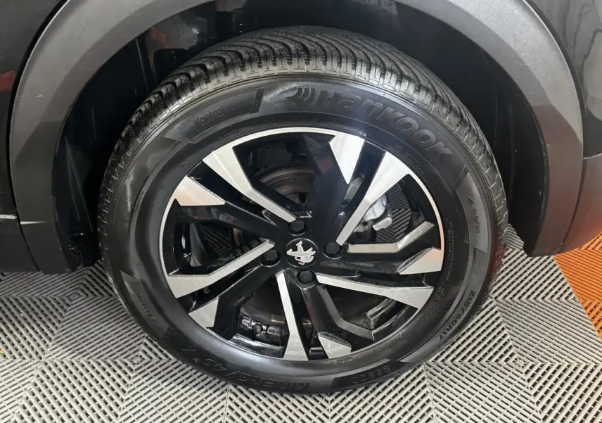 Gros plan sur la roue avant droite noire d’un Peugeot 2008 2022 avec jante alliage bicolore et pneu Hankook.