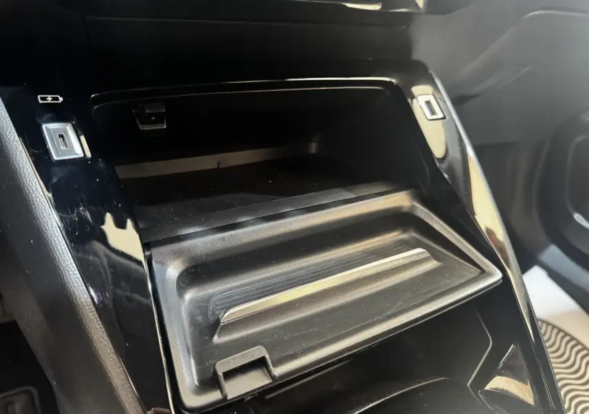 Gros plan sur la console centrale noire du Peugeot 2008 2022, montrant un rangement avec ports USB et prise 12V.