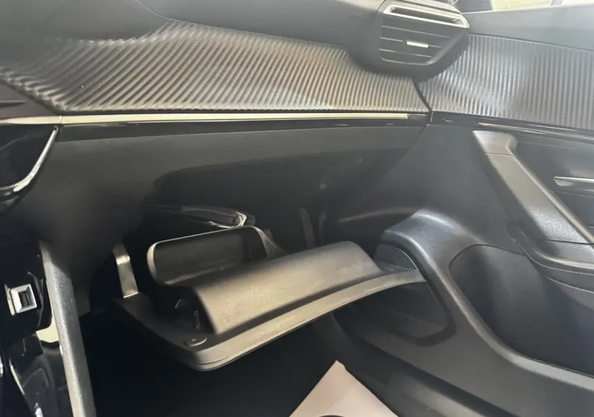 Intérieur côté passager du Peugeot 2008 2022, vue sur la boîte à gants ouverte et le tableau de bord noir avec insert carbone.