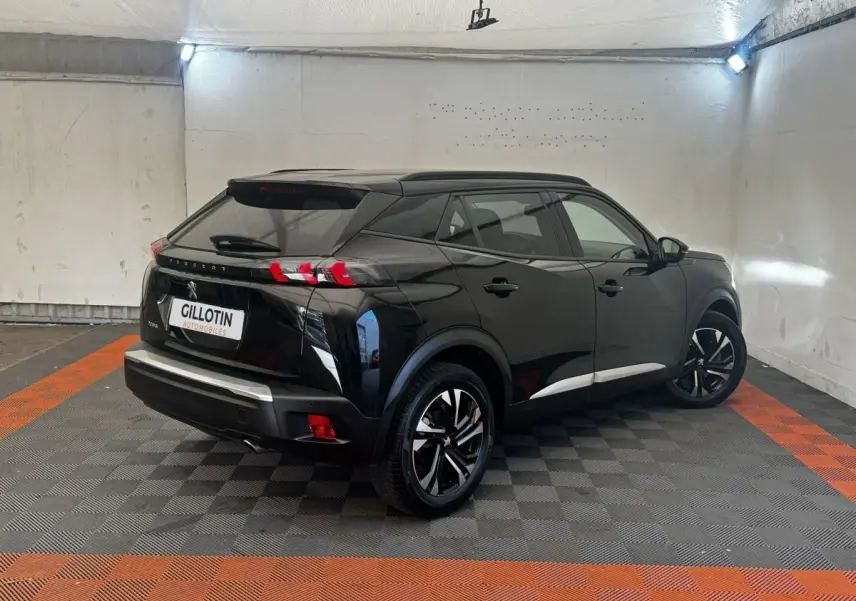 Peugeot 2008 noir vue 3/4 arrière droit dans un garage, avec jantes noires et feux arrière LED distinctifs.