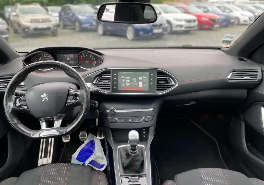 Intérieur de la Peugeot 308 SW 2017 avec tableau de bord noir, volant cuir perforé et console centrale avec écran tactile.
