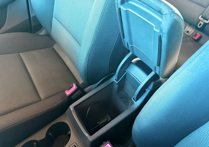 Vue intérieure centrée sur l'accoudoir ouvert et les sièges avant en tissu noir de l'Audi Q3 2016.