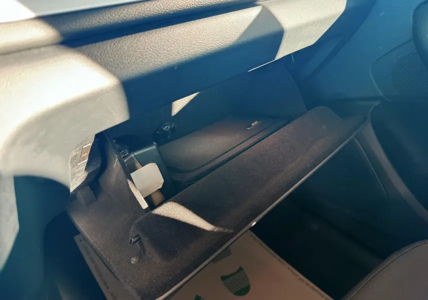 Vue intérieure du vide-poche ouvert côté passager de l'Audi Q3 noir, montrant un rangement avec un étui noir à l'intérieur.