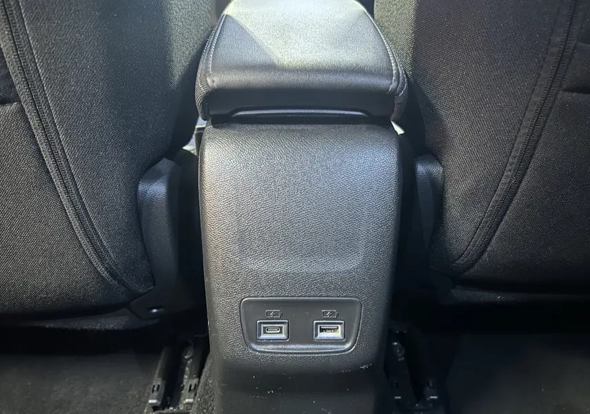 Vue rapprochée de la console centrale arrière noire du Peugeot 2008 bleu, avec ports USB visibles entre les sièges.