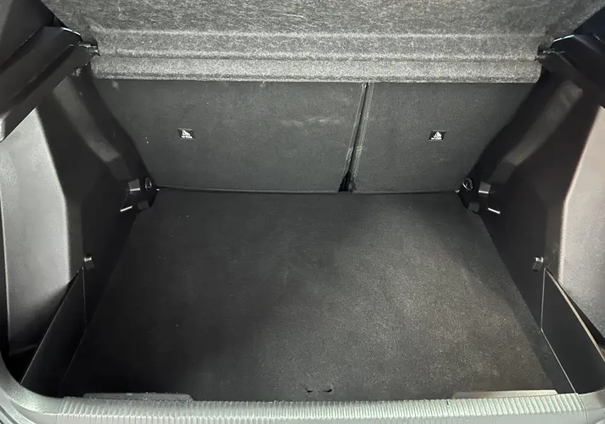 Vue intérieure du coffre spacieux et vide du Peugeot 2008 II Ph.2 Allure Hybrid 145, revêtement noir uniforme.