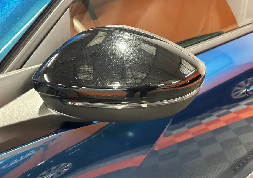 Rétroviseur extérieur noir brillant côté gauche sur Peugeot 2008 bleu Obsession, vue rapprochée en intérieur.