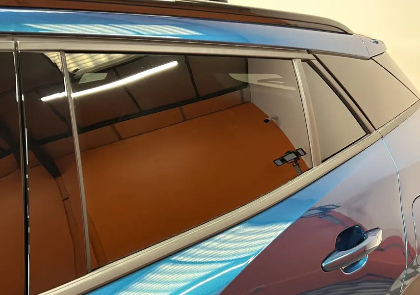 Vue rapprochée du côté gauche arrière d’un Peugeot 2008 bleu Obsession avec vitres teintées et poignée de porte visible.